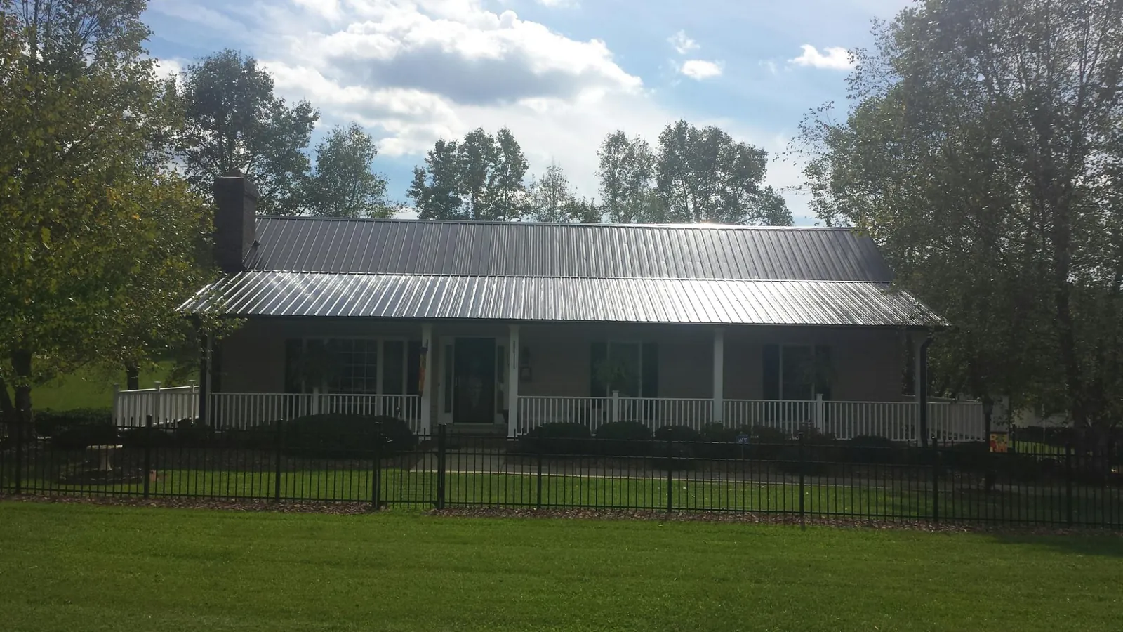 Gray metal roof on a brick ranch with a full width front porch — Gutter Guard Installation work by our crew in Norcross