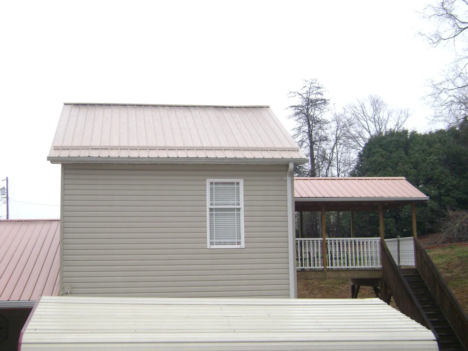 Tan metal roofs on a two story addition and attached porch, from a Roof Replacement job in Norcross